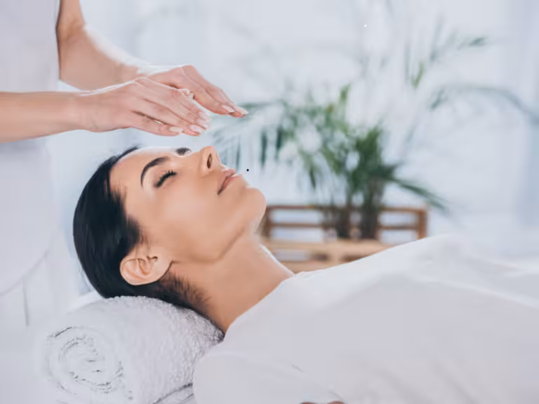 Terapeuta especializado do Instituto Ahau realizando sessão de Reiki com imposição de mãos, canalizando energia universal para equilíbrio emocional e bem-estar integral do paciente