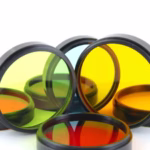 Óculos coloridos de cromoterapia ocular sobre superfície iluminada, representando o tratamento com cores para regulação do sistema nervoso e equilíbrio emocional.